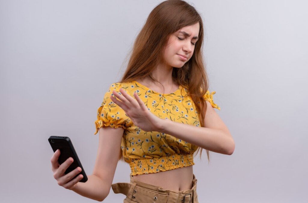 girl annoyed from smartphone pointing hand at smartphone