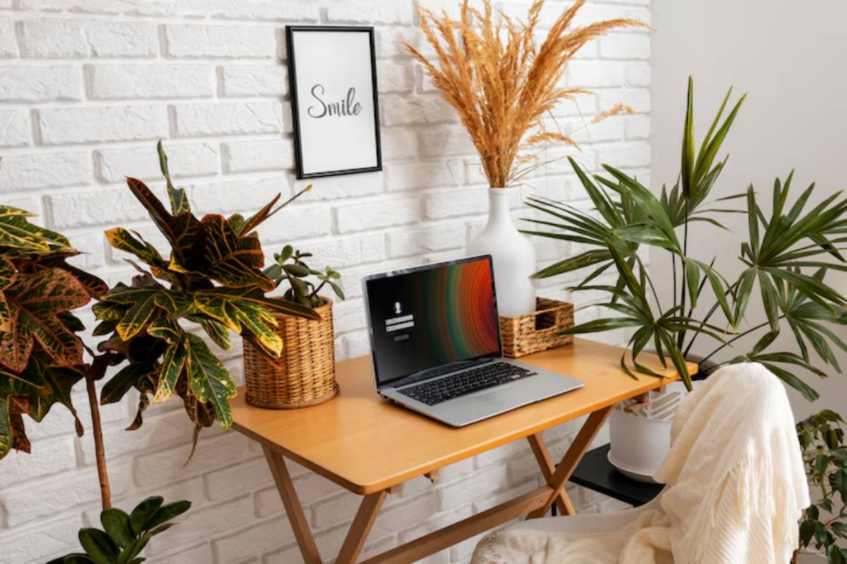  A cozy workspace featuring a laptop on a wooden desk, surrounded by potted plants and a Smile wall art.