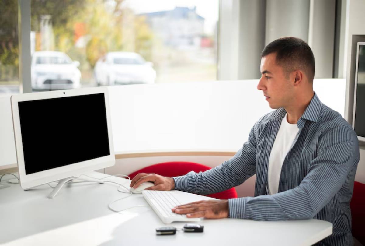  A man sitting at a desk in an office building, using a computer.