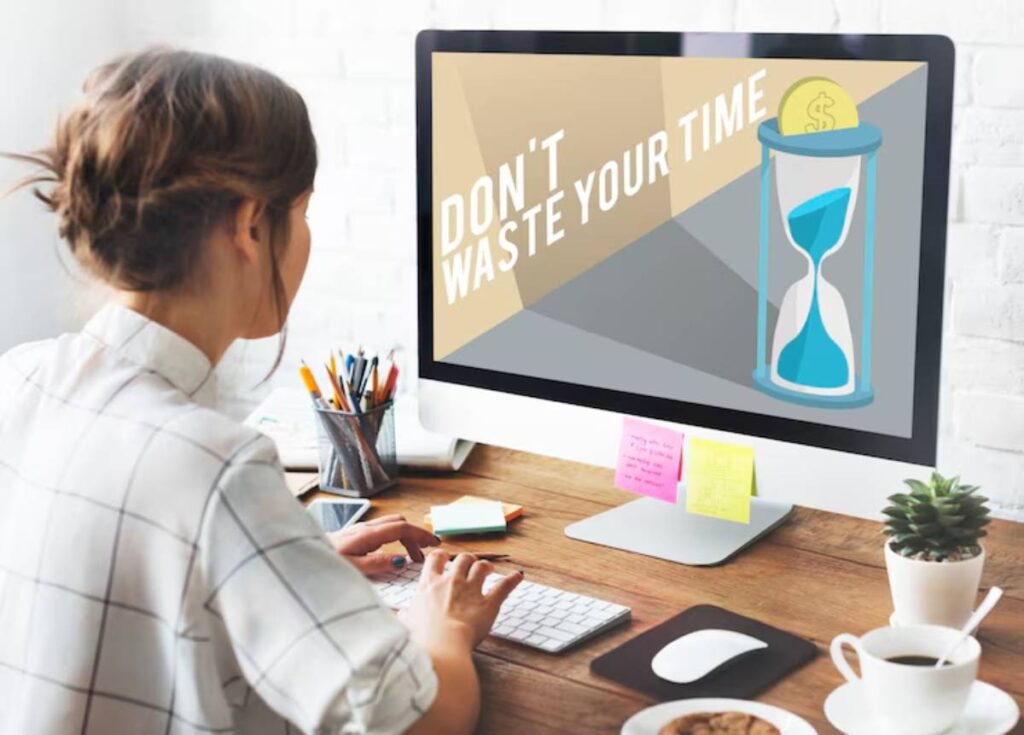 A person working at a desk, viewing a computer screen with the message, Don't waste your time, alongside an hourglass and dollar sign.